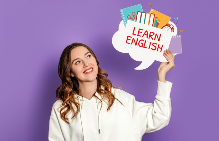 learn english concept. Caucasian girl student holding speech bubble with text learn english and illustration isolated on purple background