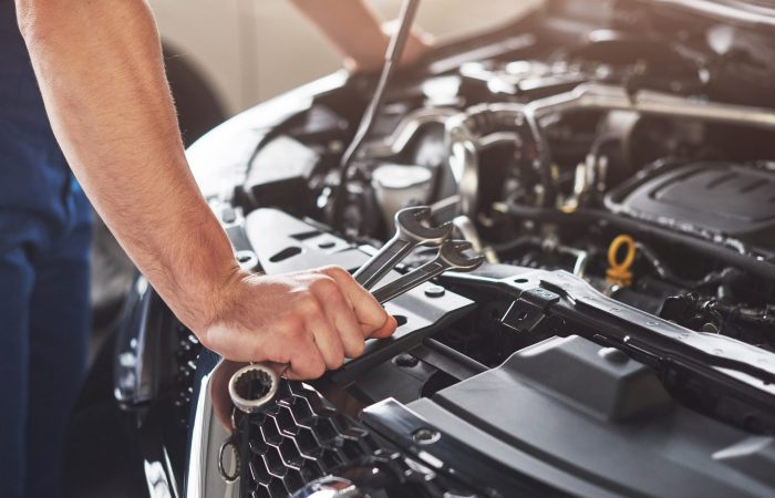 Picture showing muscular car service worker repairing vehicle.