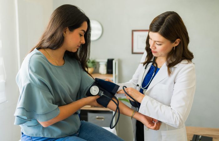 Young female patient having her blood pressure checked by a doctor during a medical examination